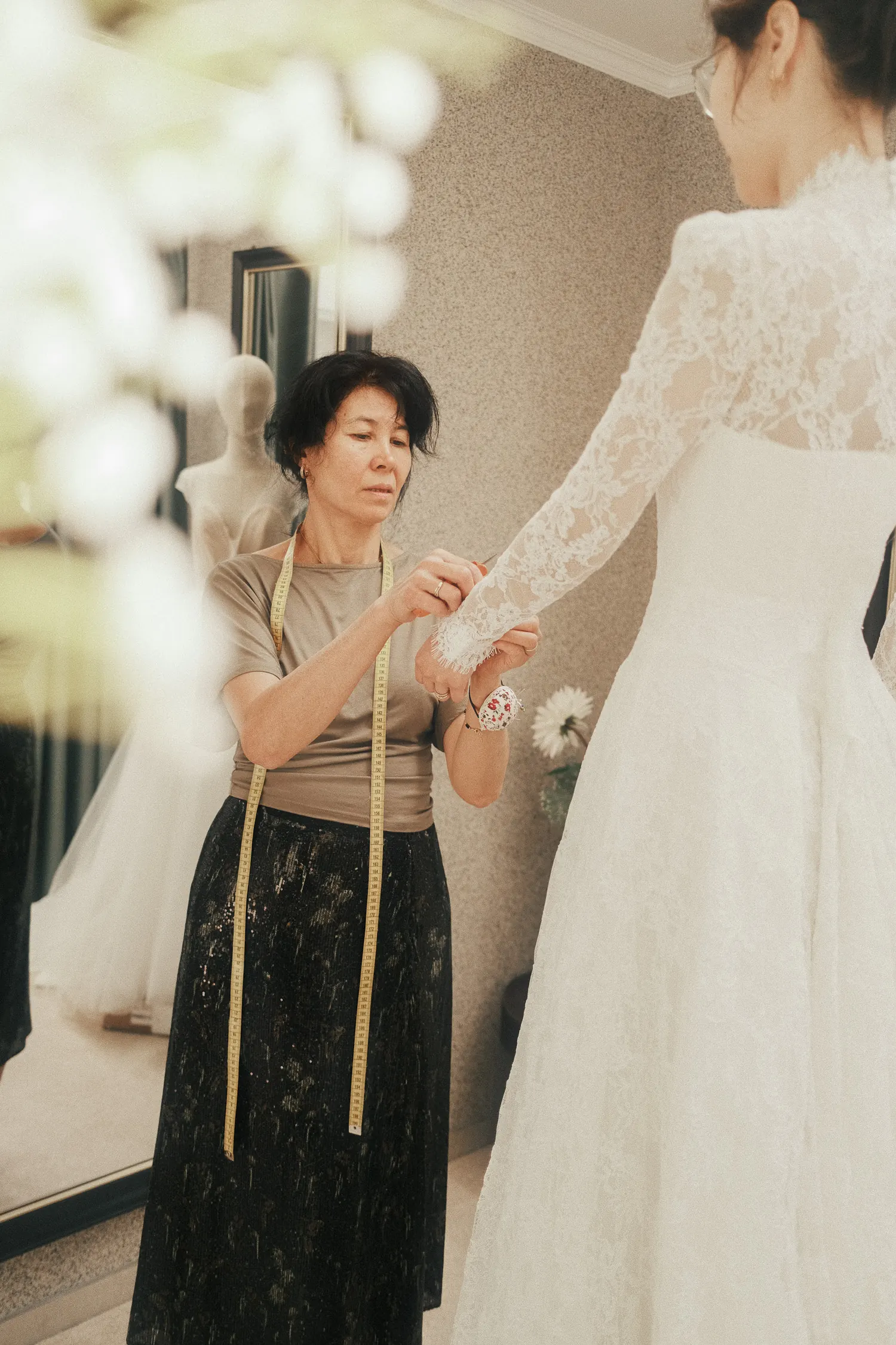 Nadilyam ajuste la manche en dentelle d’une robe de mariée pendant un essayage