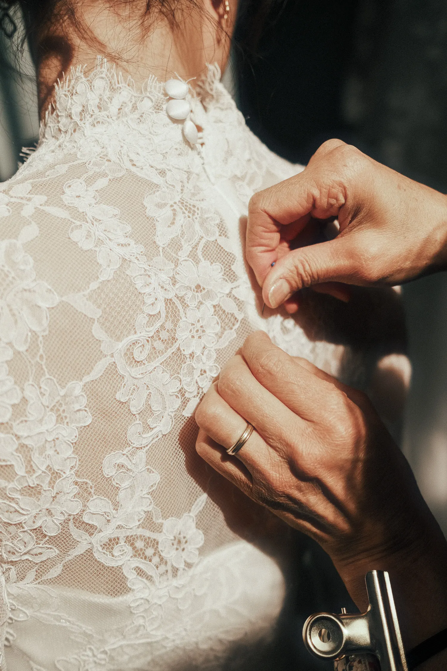 Les mains d’une couturière épinglent le dos en dentelle d’une robe de mariée