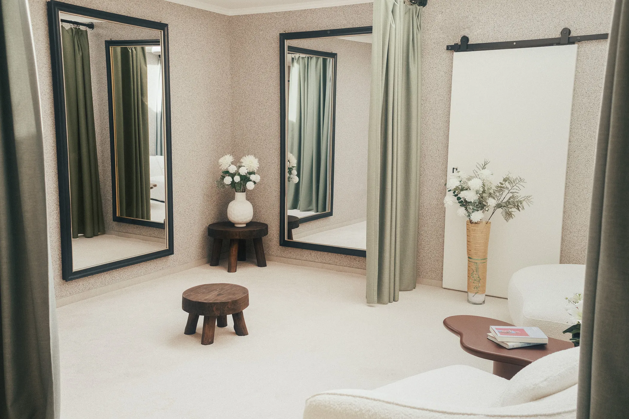 Le salon d’essayage de l’atelier, avec ses grands miroirs, ses rideaux verts et ses fauteuils clairs