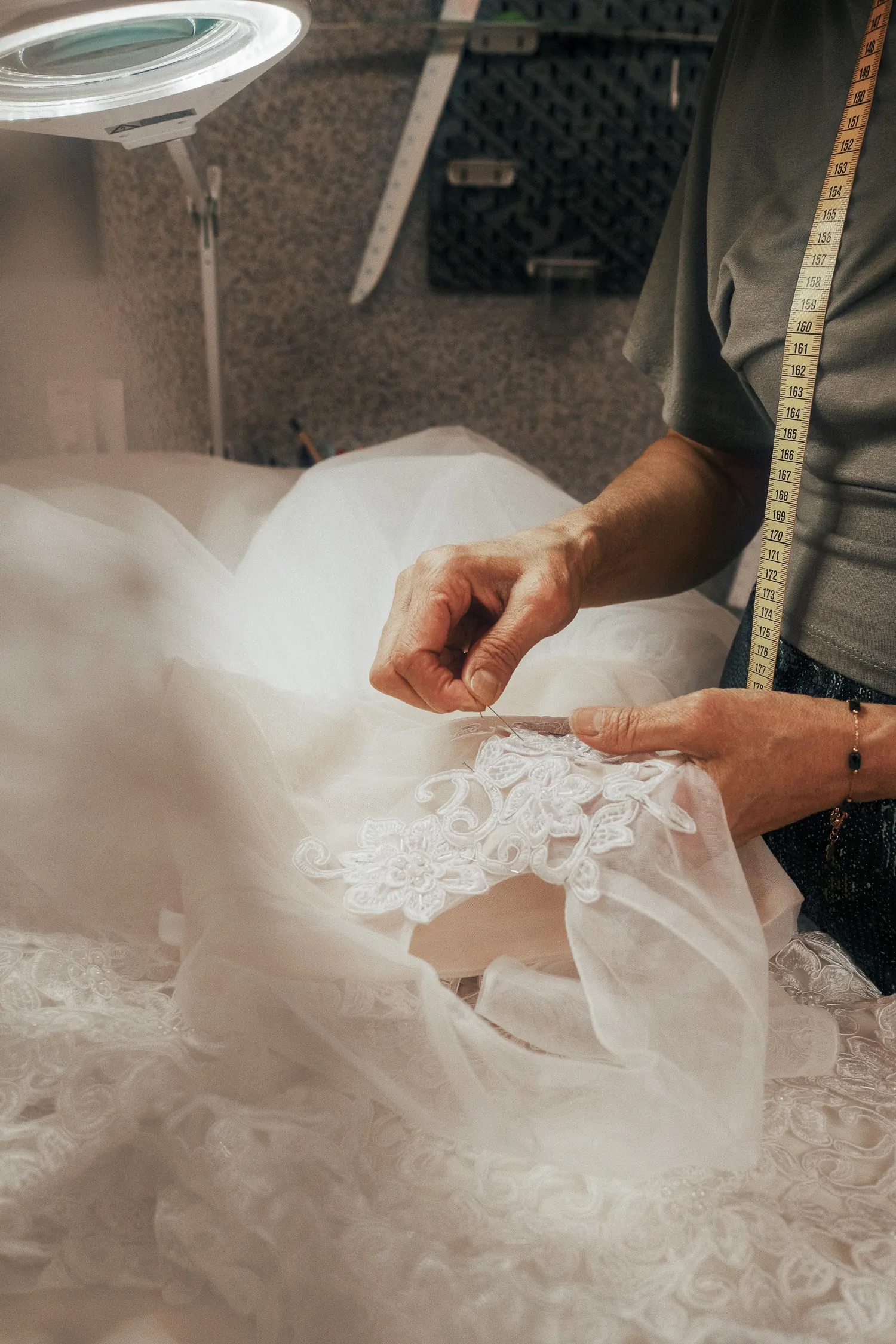 Les mains de Nadilyam cousent un motif de dentelle sur un tulle