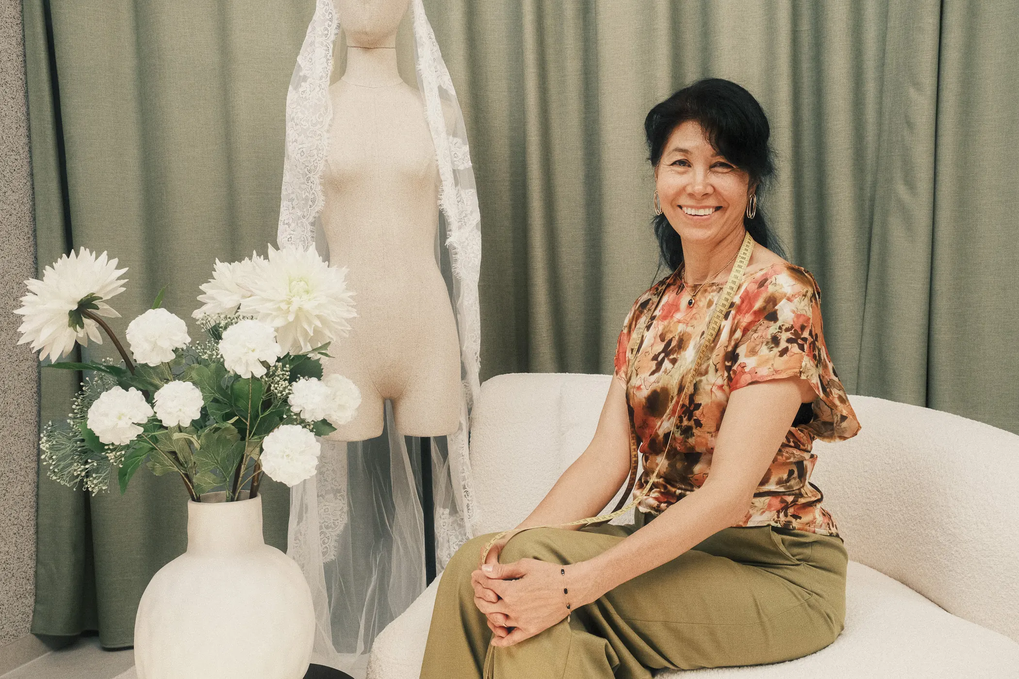 Nadilyam souriante, assise dans l’atelier près d’un mannequin portant un voile en dentelle